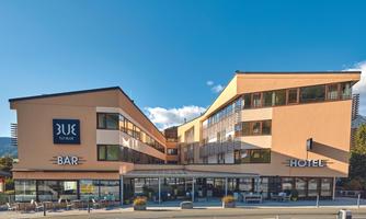 A modern hotel building named "Blue" with a bar. The facade is friendly and inviting, surrounded by a clear sky.