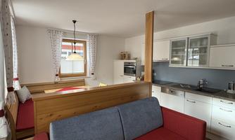 A bright and modern kitchen with a dining table and a couch. The decor is designed to be friendly and cozy.