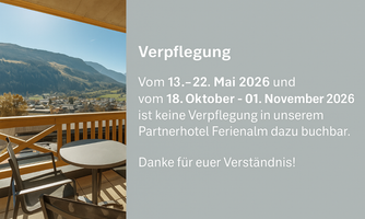 A beautiful view from the balcony of an alpine landscape with mountains and a clear blue sky. There is a table and chairs on the balcony.
