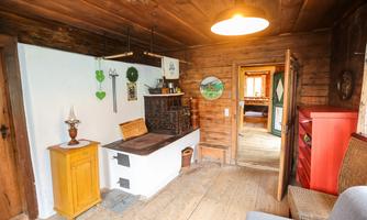 A cozy interior with wooden paneling and rustic furniture. The image shows a cooking area and a small table.