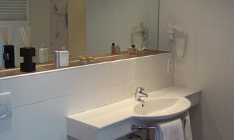 A modern bathroom with a minimalist sink and a large mirror. The walls are light, and the atmosphere is clean and welcoming.