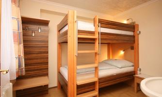 A simple room with a wooden bunk bed. There is also a small wardrobe and a table.
