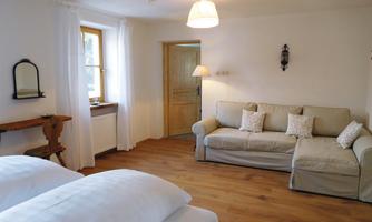 An inviting room with a cozy sofa and two comfortable beds. Large windows provide plenty of daylight and a bright atmosphere.