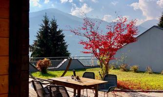 A cozy outdoor area with a wooden table and chairs. In the background, mountains and a clear sky can be seen.