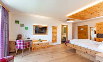 A modern bedroom with wooden furniture and plenty of natural light. The room is cozy and well-designed, ideal for a relaxing stay.