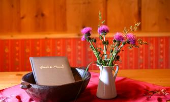 A rustic table with a decorative bowl, a flower pot, and a book. The flowers are colorful and give the ambiance an inviting atmosphere.