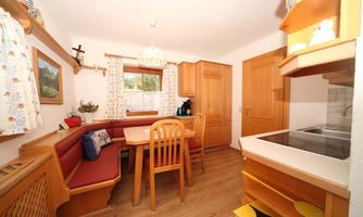 A cozy kitchen with wooden cabinets and a dining area. The room is bright and inviting, with a window that lets in light.