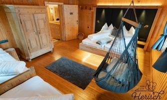 A cozy bedroom with wood paneling and two beds. A hammock invites you to relax.