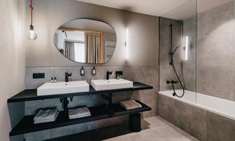 A modern bathroom with a double sink and a large mirror. There is a shower and a bathtub, both designed in a simple, elegant style.