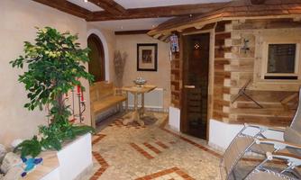 A relaxing wellness area with a sauna and a cozy lounging area. The furnishings are made of wood, surrounded by plants and an inviting atmosphere.