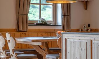 A cozy dining area with a wooden table and chairs. The window offers a beautiful view of nature.
