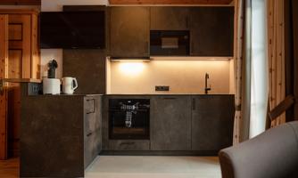 A modern kitchen with dark furniture and a bright countertop. It is well-equipped with an oven, microwave, and various kitchen appliances.