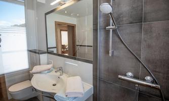 A modern bathroom with a shower and a sink. Towels are neatly placed on the sink.