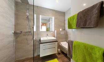 A modern bathroom with a walk-in shower and a white vanity unit. The colors are neutral with some bright green accents.