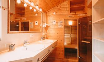 A modern bathroom with double sinks and wooden cladding. The warm colors and natural light create an inviting atmosphere.