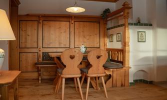 A cozy dining area with wooden-clad walls and a large table. Two chairs with heart-shaped cutouts harmoniously blend into the rustic atmosphere.
