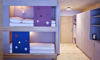 A modern room with a bunk bed and colorful accents. The walls are in soft colors, and the space feels bright and inviting.