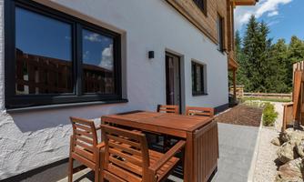 A beautiful outdoor area with a wooden table and chairs. In the background, trees and a blue sky are visible.