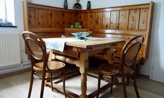 A cozy dining area with a wooden table and a corner bench. Three chairs are arranged around the table.