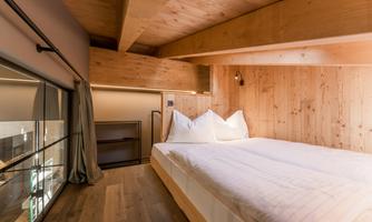 A cozy bedroom with wood paneling and a large bed. The atmosphere is warm and inviting, ideal for relaxation.