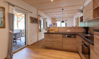 Modern kitchen with wooden surfaces and open layout. Large windows provide plenty of natural light and a connection to the outdoor area.