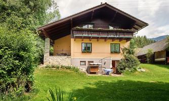 A charming alpine-style house, surrounded by green meadows and trees. The spacious garden invites relaxation.