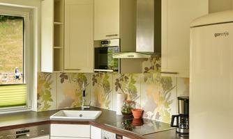 A modern kitchen with light cabinets and floral wall design. The equipment includes a stove, a sink, and a refrigerator.
