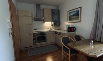 A cozy kitchen with a dining area and wooden surfaces. The room is bright and furnished in a modern style.