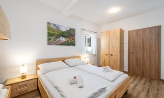 A cozy bedroom with two beds and wooden furniture. A window provides plenty of daylight and a picture on the wall gives the room a pleasant atmosphere.