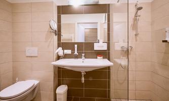 A modern bathroom with tiles in neutral colors. It includes a sink, a shower, and a toilet.