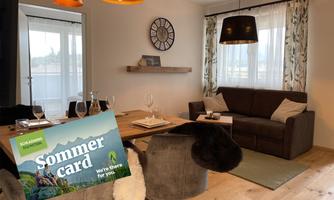A cozy living area with a dining space and a small sitting area. On the table lies the summer menu, which offers activities in the region.