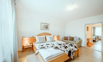 A cozy bedroom with a double bed and a sofa. The walls are light and the room is well lit.