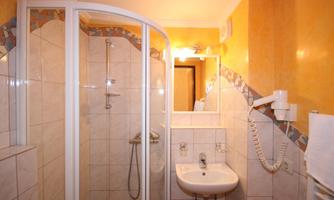 A simple bathroom with a shower cubicle and a sink. The walls are in a warm shade of yellow.