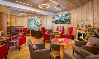 A cozy interior with wooden walls and modern furniture. A fireplace and artistic wall decorations create an inviting atmosphere.