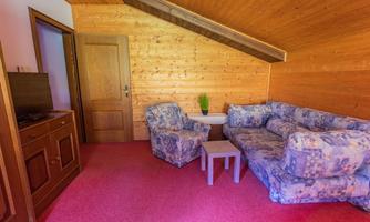 A cozy living space with wood paneling and a blue sofa. The room has a red carpet and a small table.