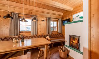 A cozy room with wood paneling and a large dining area. The fireplace creates a warm atmosphere.