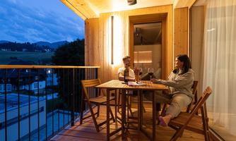 A cozy terrace at dusk with two people drinking wine. The atmosphere is relaxing and inviting.