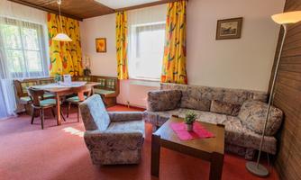 A cozy living room with a sofa and a table. The colorful curtains and the rug create a friendly atmosphere.