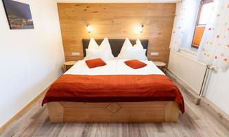 A cozy bedroom with a large bed and modern wood decor. The walls are light, and there is a pleasant atmosphere.