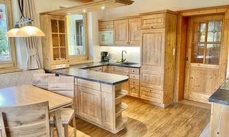 A bright kitchen with wooden cabinets and a dining area. The space has an inviting atmosphere with a large window and good lighting.