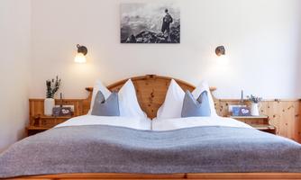 A cozy bedroom with two single beds and gray bed linen. A black and white picture hangs on the wall, along with harmonious lighting.