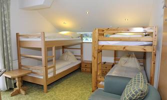 A bright room with two wooden bunk beds. There is a cozy seating area and a small table.