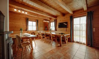 A cozy dining area made of wood with a large table and chairs. Large windows let in plenty of light and create an inviting atmosphere.