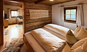 A cozy bedroom with wooden paneling and a large bed. The window offers a view of a peaceful environment.