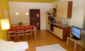 A bright and inviting kitchen with a dining table and chairs. The walls are painted in warm colors, and there is a cozy seating area.