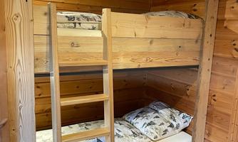 A cozy room with a wooden bunk bed. The bedding has a natural design with an animal motif.