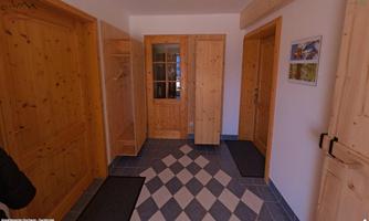 A bright entrance area with wooden paneling and a modern floor pattern. There are several doors and space for coats and shoes.