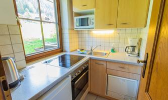 A bright kitchen unit with wooden cabinets and modern appliances. Large windows provide plenty of daylight.