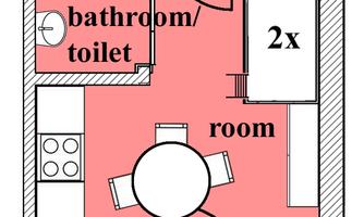 A simple floor plan drawing of an apartment. It shows a bathroom with a toilet and a room with a kitchen and dining area.