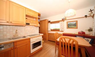 A bright kitchen with wooden cabinets and modern appliances. A cozy dining table with chairs is also available.